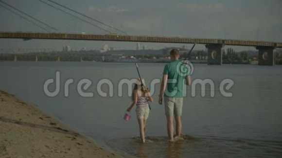 沿着河岸行走的钓鱼竿家人视频的预览图