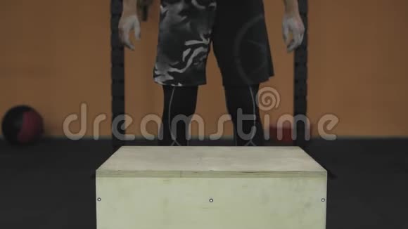 在健身房里人在木立方体上跳跃健身男子跳箱子视频的预览图