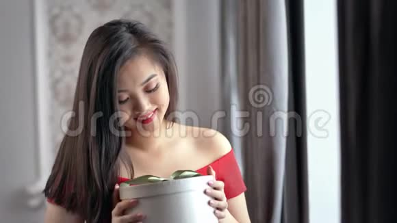 浪漫的年轻亚洲女人微笑着拿着礼品盒中等特写视频的预览图