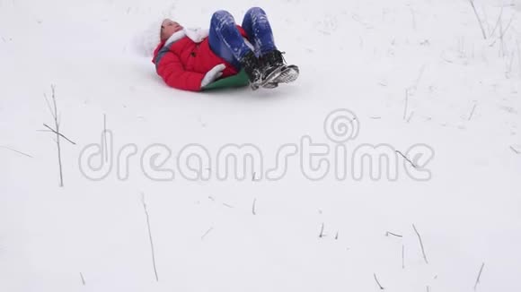 冬天女孩从山上滑下雪圣诞节期间孩子们在冬季公园玩耍慢动作视频的预览图