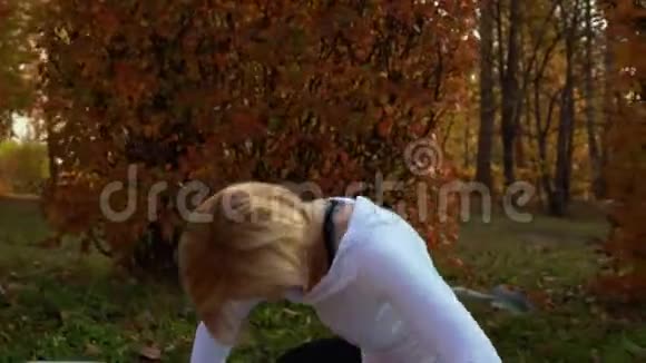 健身妇女伸展身体在地毯上户外锻炼秋季公园运动女性在城市练习瑜伽视频的预览图