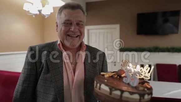 快乐可敬的老人拿着蛋糕庆祝生日周年视频的预览图