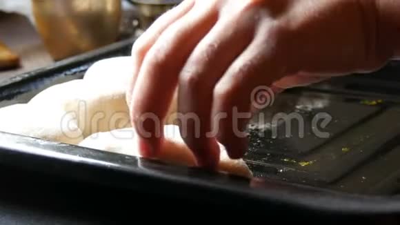 女人的手面包师把自制的烘焙面团以细长的圆球的形式连续放置在黑色烘焙片上视频的预览图