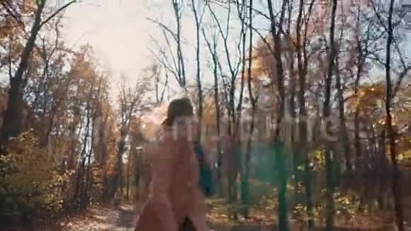 快乐的年轻女子在森林的秋天奔跑正面的景色视频的预览图