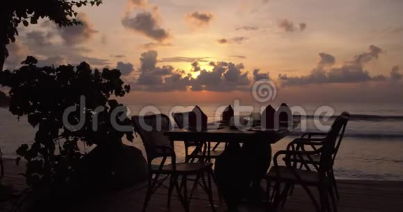 美丽的傍晚海景沙滩粉红的天空和平静的海水在露天阳台上提供晚餐视频的预览图