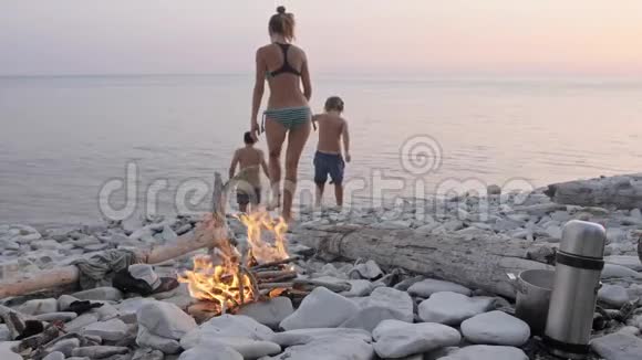 幸福的一家人在篝火旁的野生海滩上享受夏日日落视频的预览图