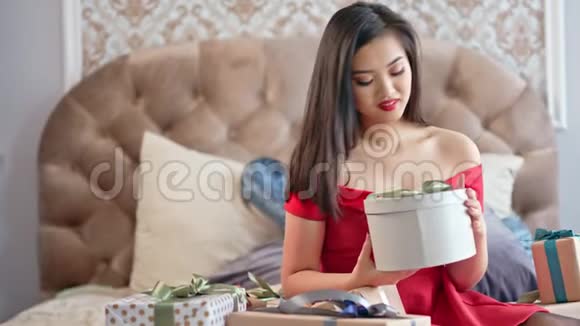 美丽的年轻女子穿着红裙子微笑着打开礼品盒对现在的中镜头感到失望视频的预览图