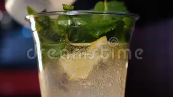 酒保把苏打水倒入装有柠檬和薄荷的塑料杯中冷饮制作过程关门视频的预览图