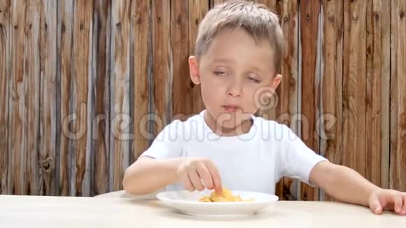 一个穿着白色T恤的孩子坐在桌子旁吃视频的预览图