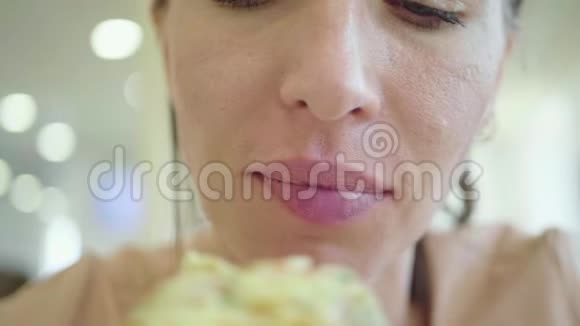 一个年轻的女人正在吃一块披萨可爱的快乐女孩笑着咬着一大片新鲜披萨视频的预览图