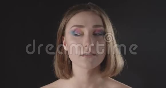 年轻漂亮的白种人短发女性的特写镜头在镜头前摆着闪亮的妆容视频的预览图