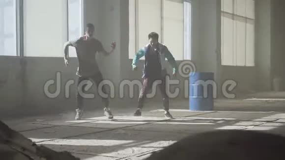 熟练街舞者的培训两个成功的舞者在废弃的尘土飞扬的建筑里跳舞视频的预览图