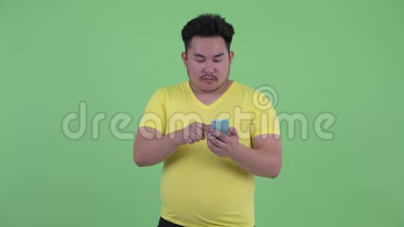 快乐年轻的超重亚洲男人用电话看起来很惊讶视频的预览图