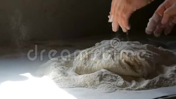 女人的手在村里的老式厨房里揉面团一缕阳光洒在面团和面粉上视频的预览图
