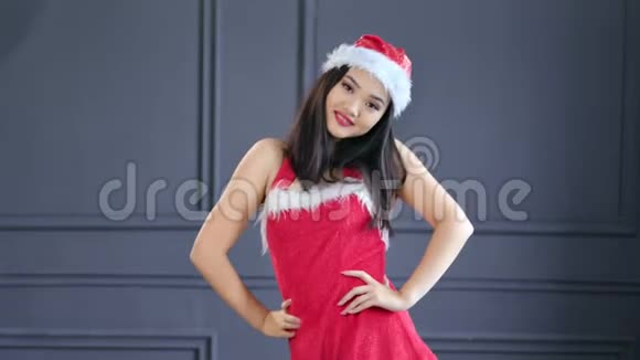 带着圣诞老人的帽子西装跳舞在演播室里玩得开心快乐的年轻女孩视频的预览图