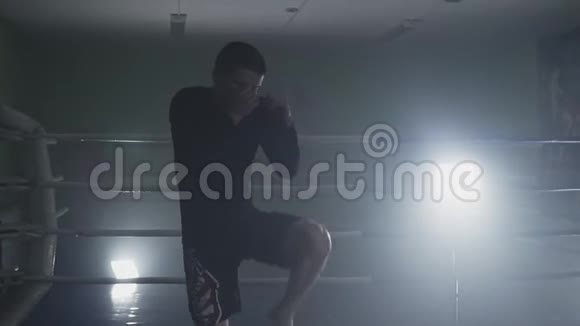 在slomo的低光健身房踢拳击手训练烟雾缭绕的健身房里的运动员视频的预览图