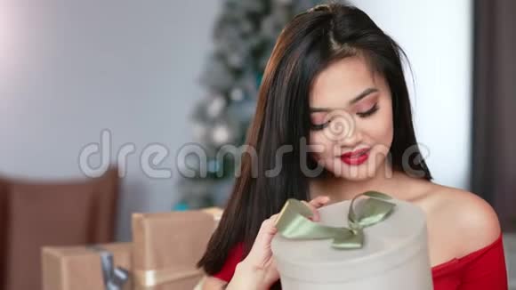 充满好奇心的年轻亚洲女人打开圣诞礼物盒微笑的中等特写肖像视频的预览图