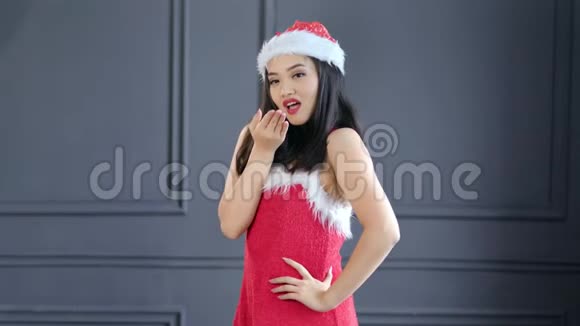 勾引年轻的亚洲圣诞老人女孩亲吻一只手吹吻中镜头的肖像视频的预览图
