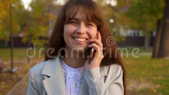年轻漂亮的女人在公园里用手机说话快乐的女孩微笑英译汉1漂亮的女商人手里拿着视频的预览图