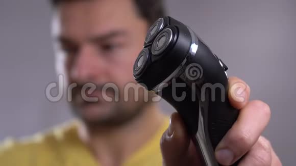 一个年轻人用电动剃须刀刮胡子的特写镜头视频的预览图