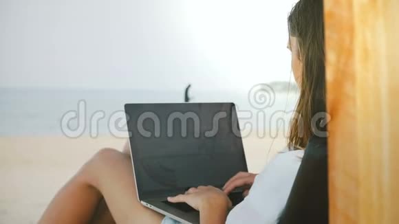 在异国海滨的笔记本电脑移动办公图上工作的快乐成功女性自由职业者的背景视频的预览图