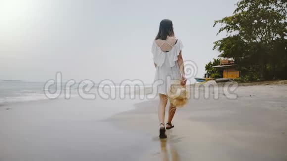 慢动作后景快乐年轻迷人的旅行者女性在异国情调的热带海洋海滩缓慢行走视频的预览图