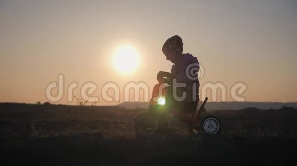 日落背景下骑自行车的女孩的剪影孩子在夕阳下玩自行车视频的预览图