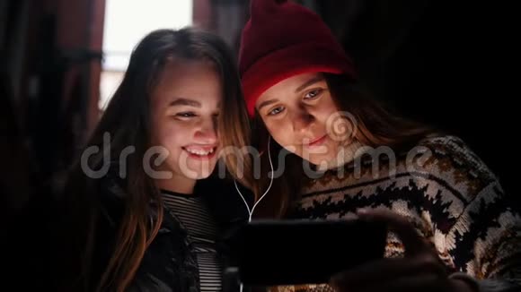 两个微笑的年轻女人站在街上看着手机屏幕视频的预览图
