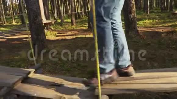 摄像机跟踪公园树上的绳桥上的人腿视频的预览图