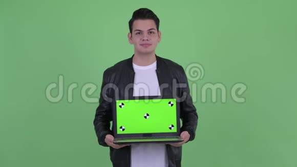 快乐的年轻英俊的多民族男人一边思考一边展示笔记本电脑视频的预览图