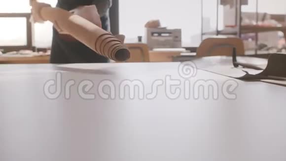 专业工匠商人将一大块皮革铺在轻型制造车间桌上的特写镜头视频的预览图
