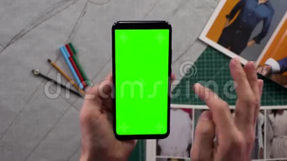 男士们的特写双手握着智能手机在背景衣柜里竖着绿色屏幕准备着衣服视频的预览图