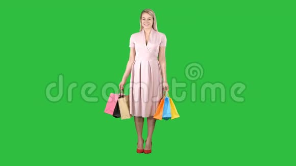 快乐的年轻女子转身手里拿着购物袋看着绿色屏幕上的相机Chroma键视频的预览图