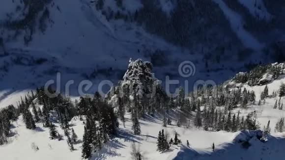 空中无人机绕着森林中雪山上的悬崖飞行视频的预览图