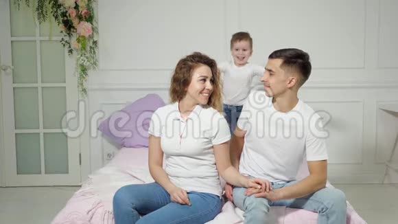 小男孩抱着他的父母坐在床上视频的预览图