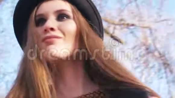 一位身穿深色帽子和黑色皮夹克的漂亮年轻女子的特写镜头她的妆容时尚看着春天的相机视频的预览图