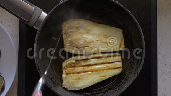 茄子切片用黄油在煎锅里煎女性用刀将手翻过来特写顶部视频的预览图