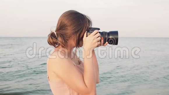 年轻的女摄影师沿着海滨散步拍照片女孩在日落时度假爱好自负视频的预览图