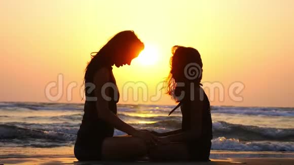 在美丽的夕阳下妈妈和女儿一起在海洋上冥想视频的预览图
