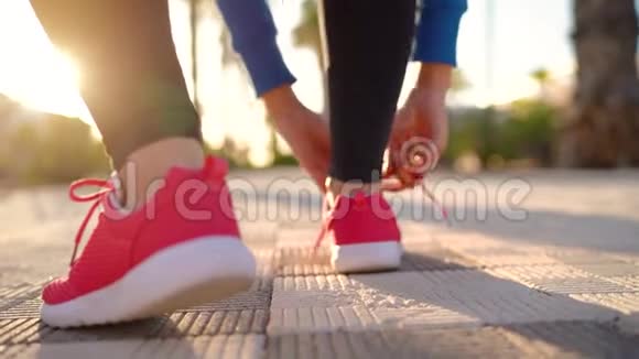 在日落时分女人系鞋带沿着棕榈大道奔跑后景以不同的速度拍摄视频的预览图