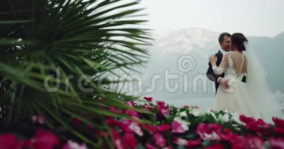 将新娘和新郎安置在山中央令人惊叹的地方背景是湖多色的花朵和视频的预览图