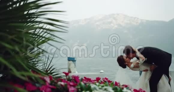 美丽的新娘穿着白色长裙与新郎在美丽的地方浪漫地接吻美丽的风景视频的预览图