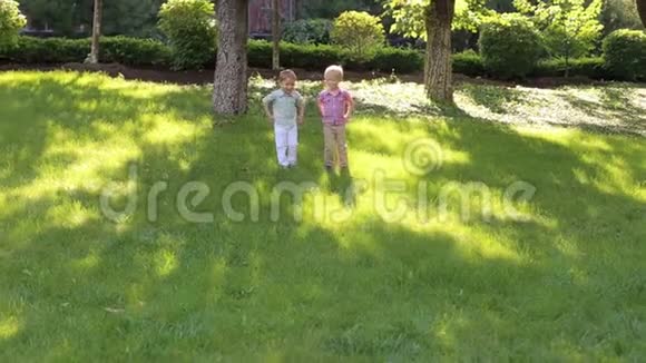 日落时分两个小孩在公园的草地上奔跑视频的预览图