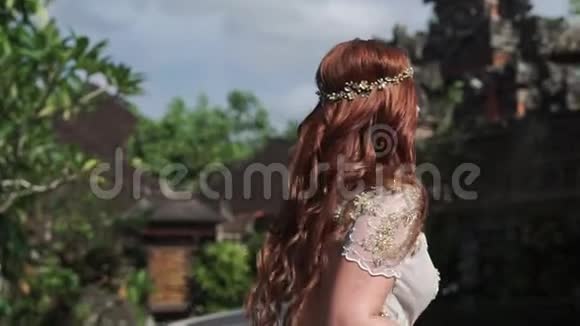 美丽的新娘在巴厘岛的佛寺附近奔跑在附近散步浪漫的婚礼视频的预览图