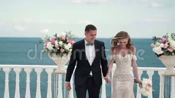 婚礼上的新娘和新郎一对恋爱中的年轻夫妇穿过客人投掷玫瑰花瓣视频的预览图