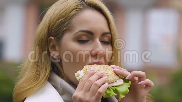 年轻漂亮的女士吃汉堡垃圾食品的危害消化问题的风险视频的预览图