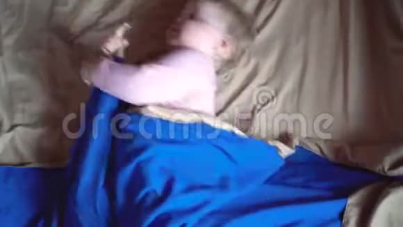 一个可爱的小醒了的幼儿在蓝色的毯子里旋转然后在它的一侧转动然后结冰小宝贝女儿视频的预览图