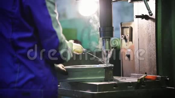 一个人在金属零件上进行钻孔工作将液体倒入材料中视频的预览图