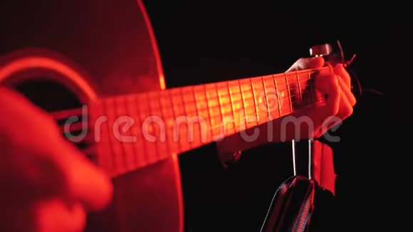 用红色背光和黑色背景演奏声学吉他视频的预览图