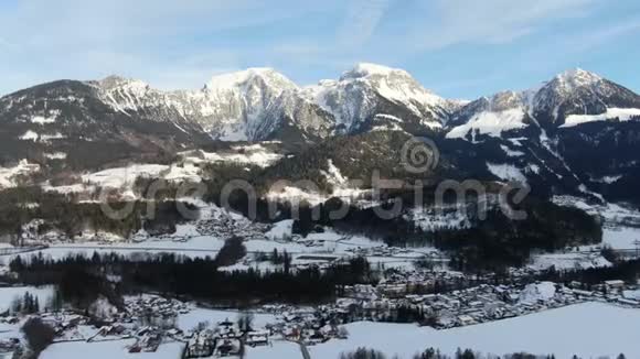 空中拍摄的山脉有很多雪和一个小村庄4k视频的预览图